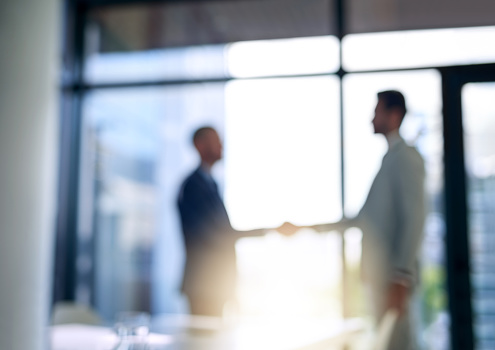 Blurred shot of two businessmen shaking hands in a modern office